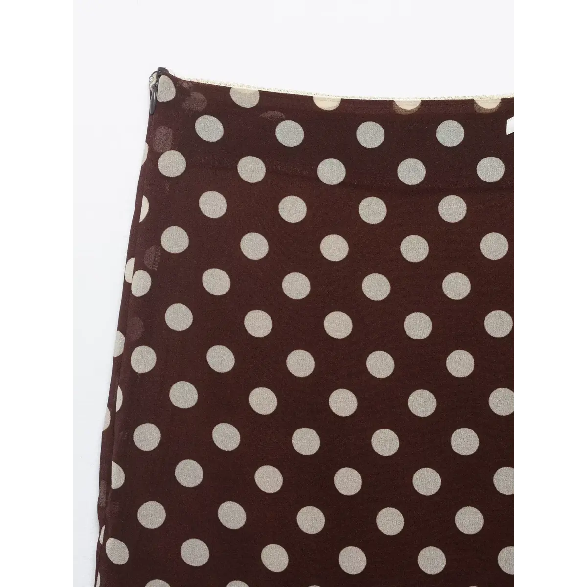 Close-up of the polka dot print pattern and fabric texture on the brown mini skirt