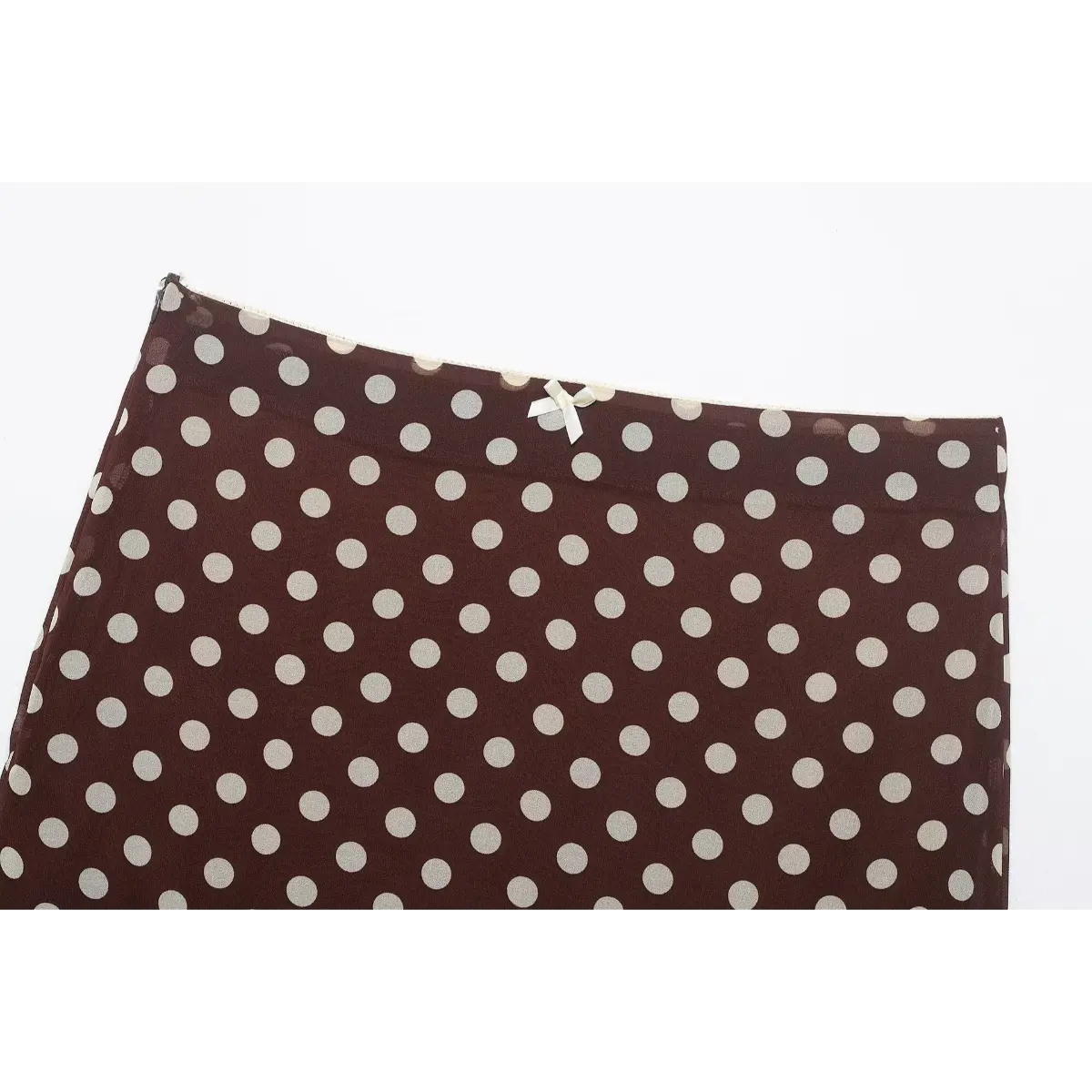 Close-up of the high waistband and small bow detail on the brown polka dot skirt