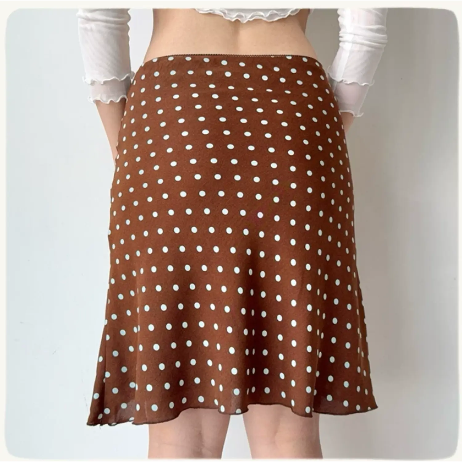 Back view of a brown polka dot chiffon midi skirt, showing the fabric drape