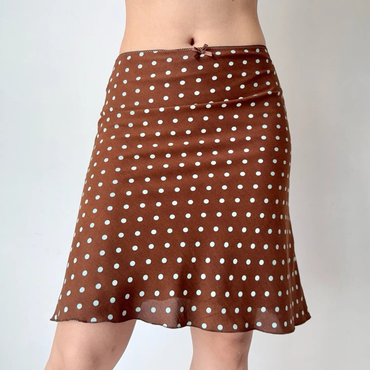 Close-up shot of a brown polka dot chiffon midi skirt with a small bow detail at the waistband