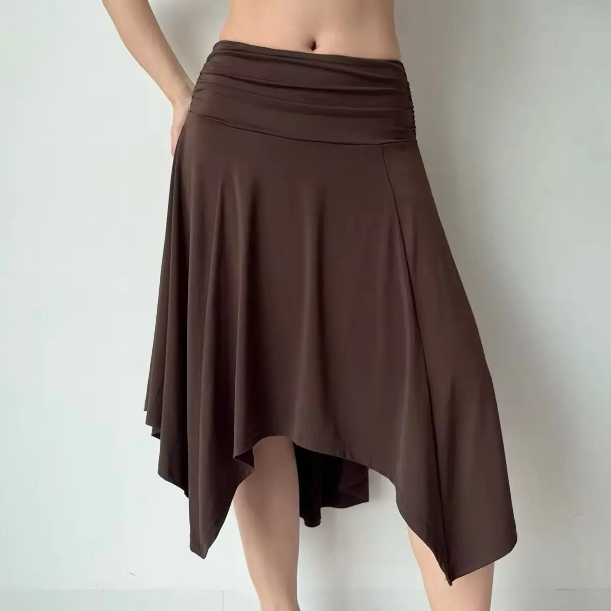 Front view of a brown asymmetrical midi skirt with a ruched waistband, featuring the same fluid handkerchief hem design.