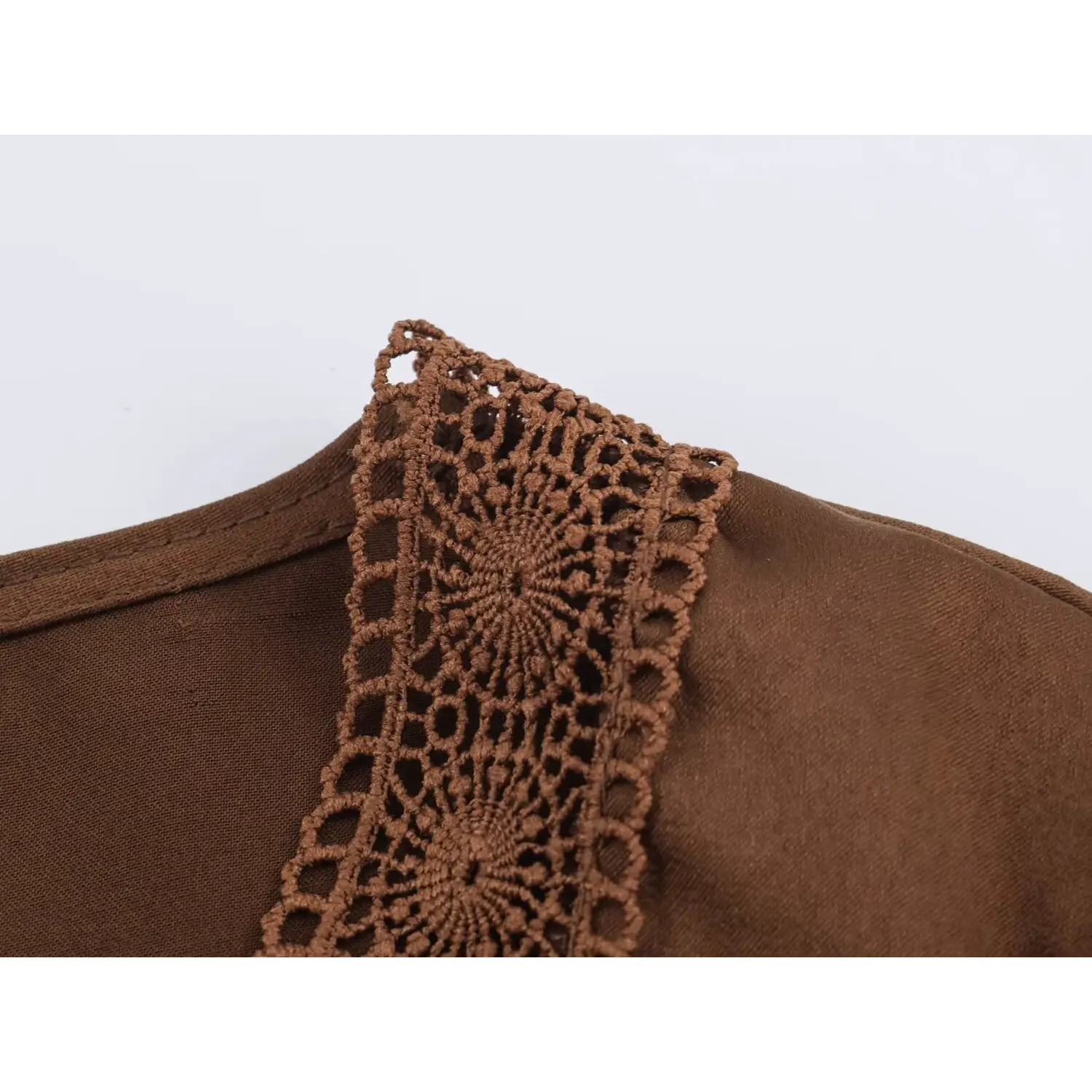 Detailed close‑up of crochet lace trim on brown satin maxi dress neckline