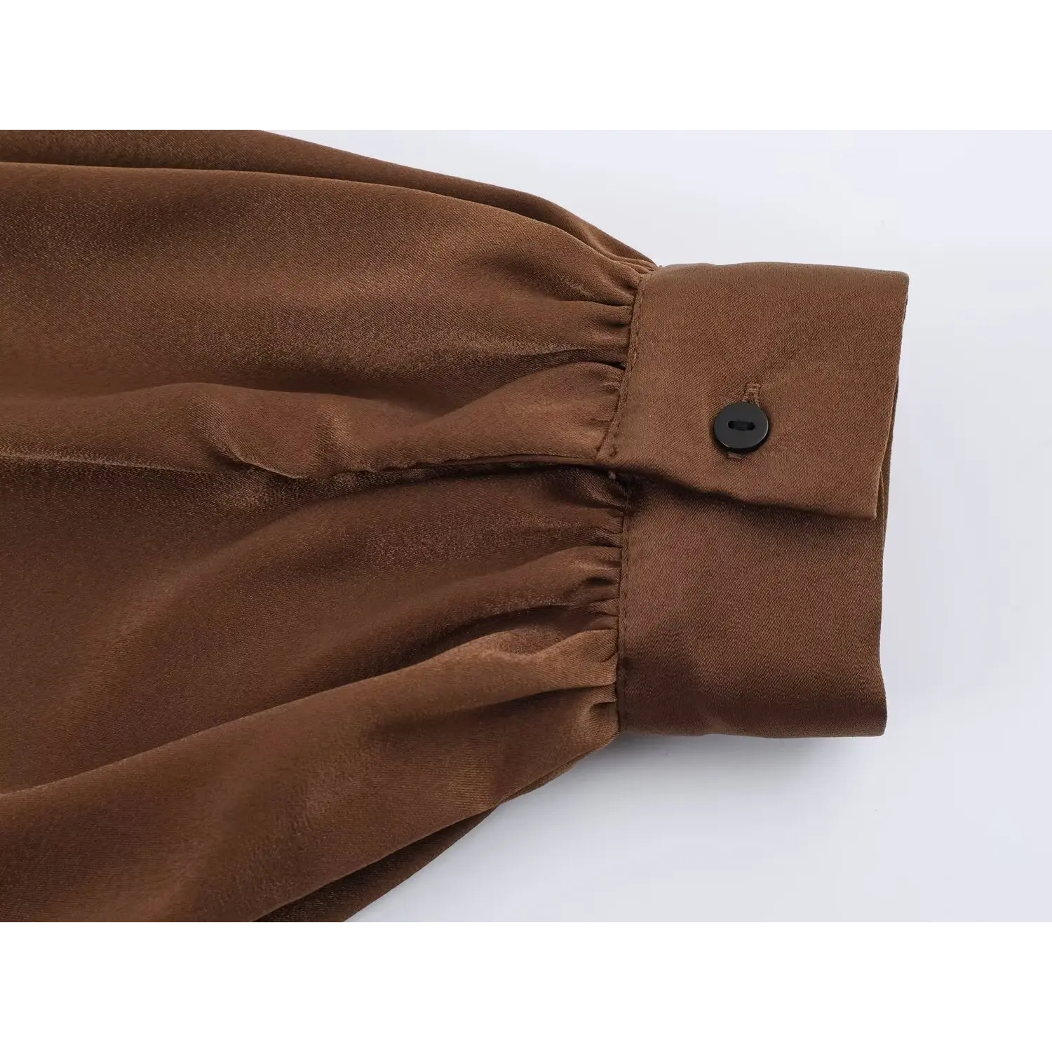 Close‑up of long sleeve cuff with black button on brown satin maxi dress