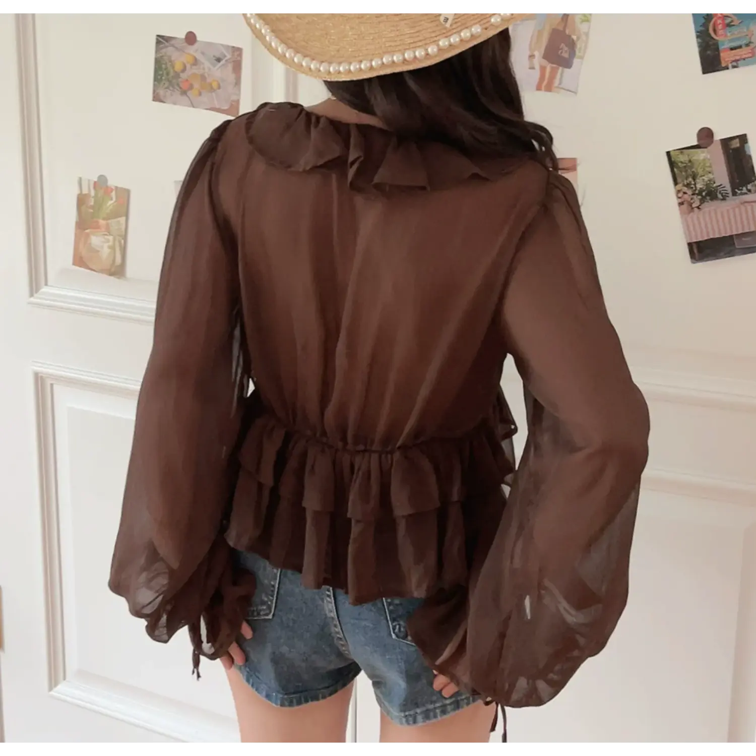 Brown sheer chiffon crop top model back lifestyle shot, full back elastic smocked waist back neck ruffle sheer long sleeve match denim shorts vintage caramel travel outfit display