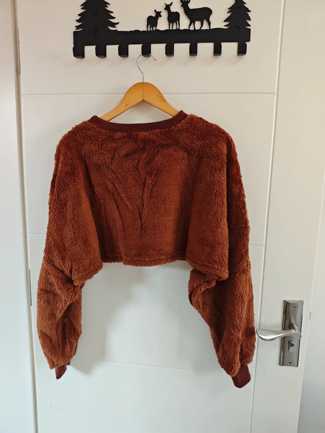 Brown teddy fleece crew neck cropped sweatshirt hanging on door, back view