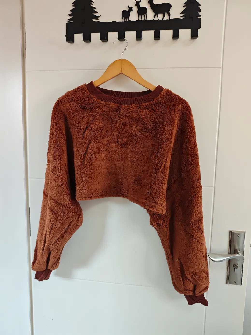 Brown teddy fleece crew neck cropped sweatshirt hanging on door, front view
