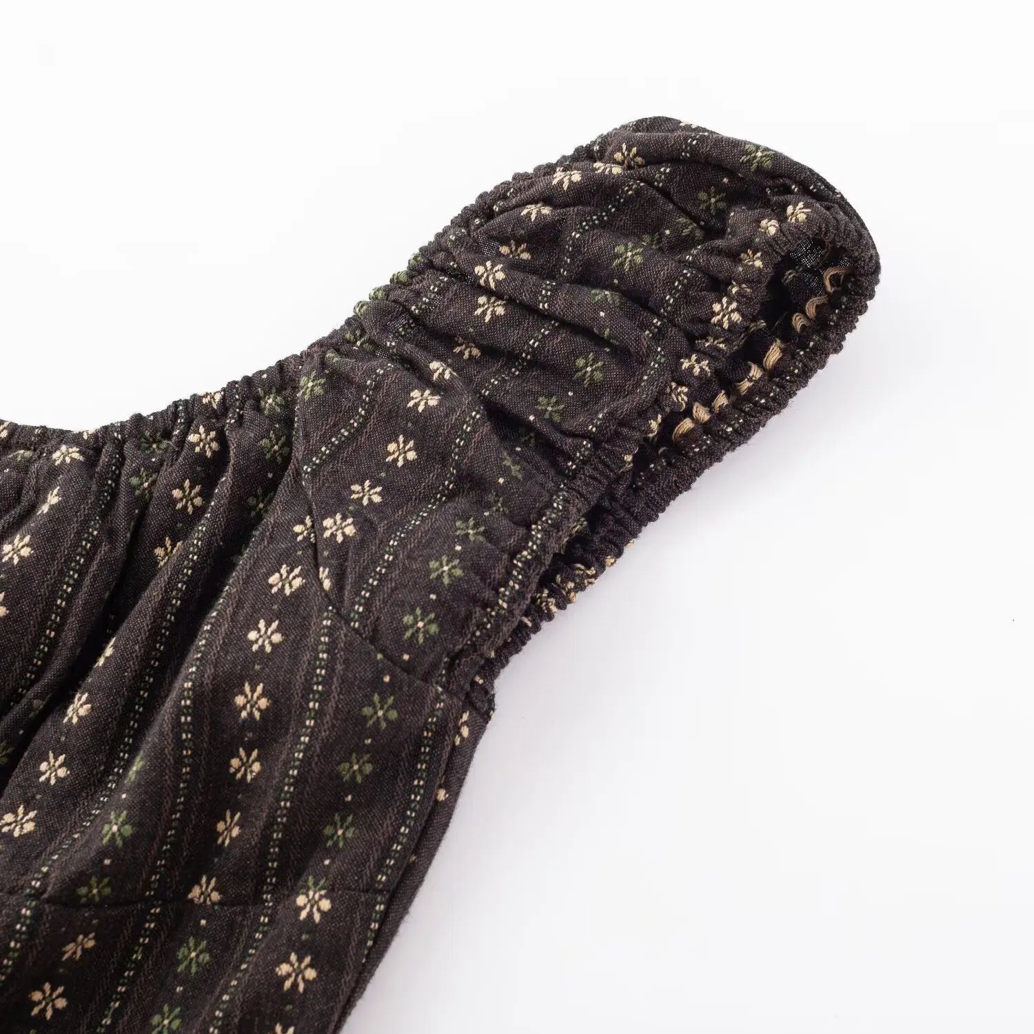 Dark brown vintage floral crop top single strap flat close-up, full elastic ruched cap sleeve and stitched printed woven fabric seam