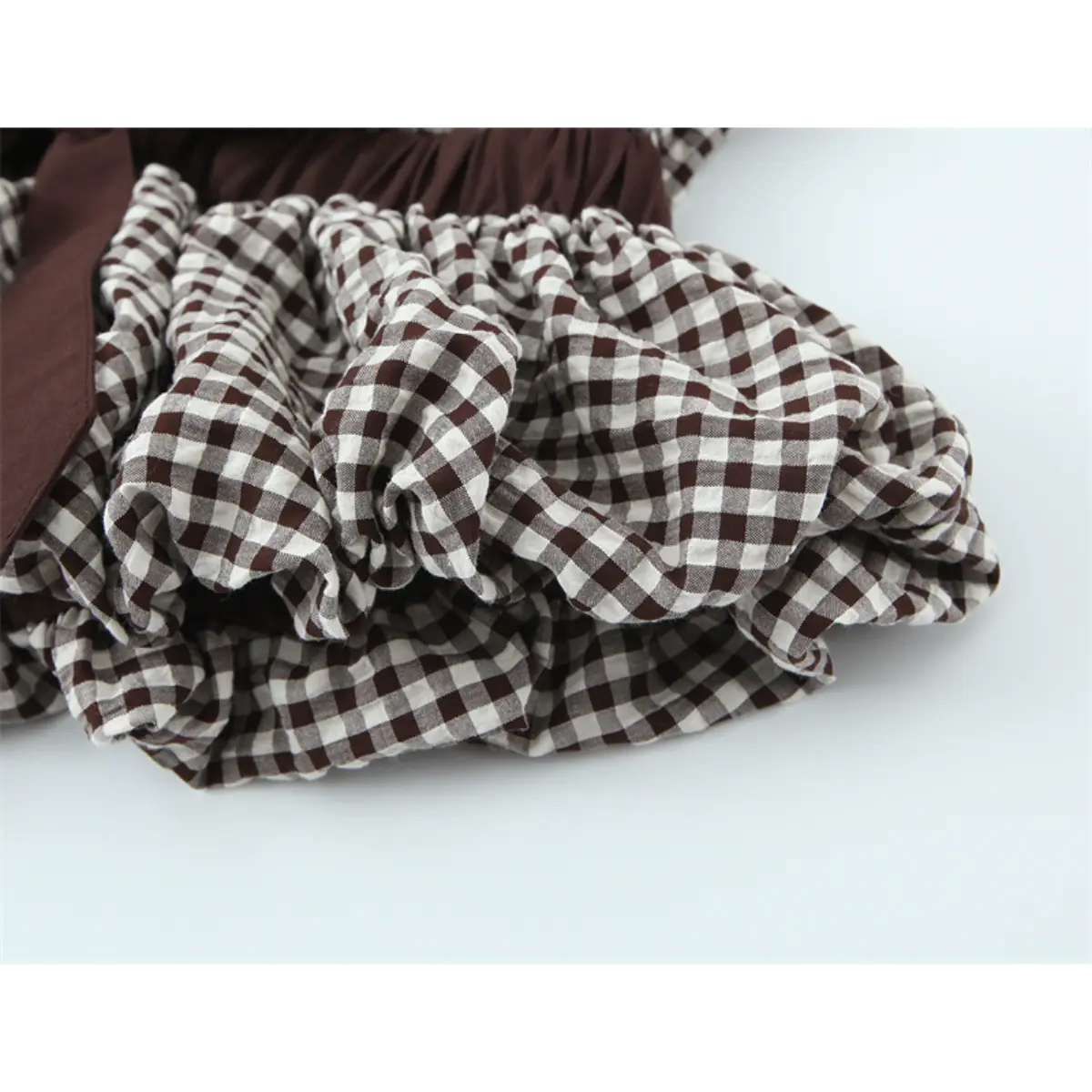 Close-up of the ruffled hem on the gingham top, showing the gathered texture and checkered pattern