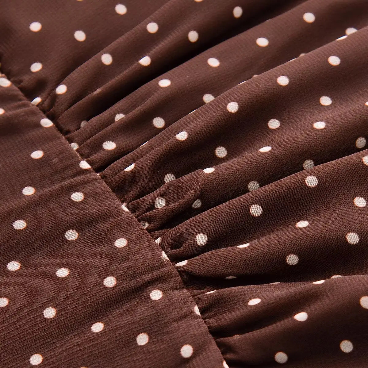 Close-up detail of the gathered waist construction on a brown and white polka dot chiffon dress.