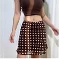 Close-up view of a brown and white polka dot chiffon mini skirt, showing the delicate print and lace-trimmed waistband, paired with a brown ribbed crop top.
