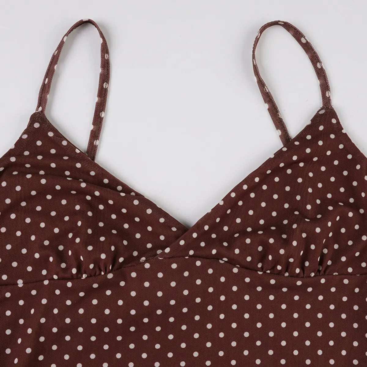 Full front view of the bust area of a brown mesh dress with white polka dots, showing the V-neckline, spaghetti straps, and polka dot pattern.