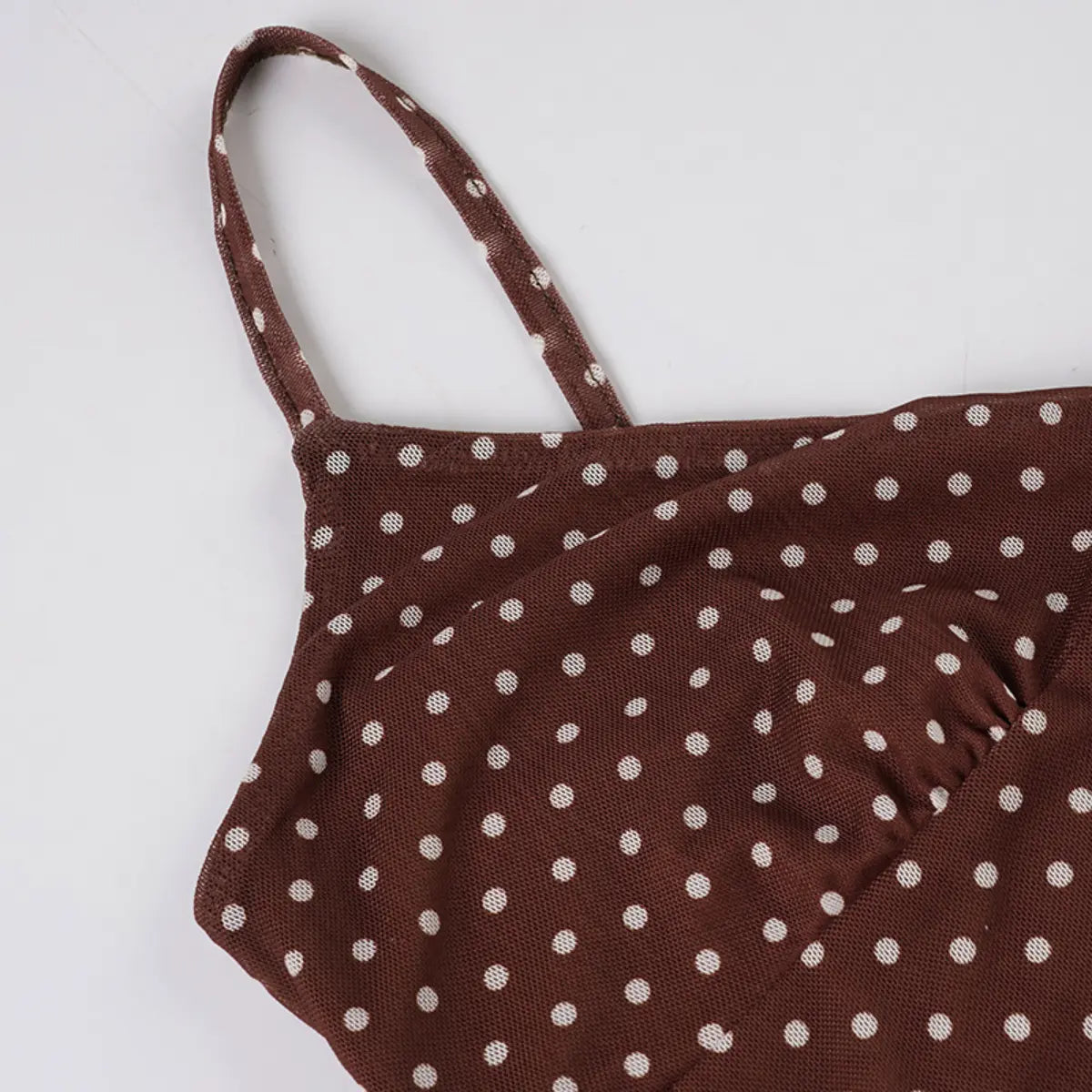 Close-up view of the spaghetti strap on a brown mesh dress with white polka dots, showing the print placement and sheer texture.
