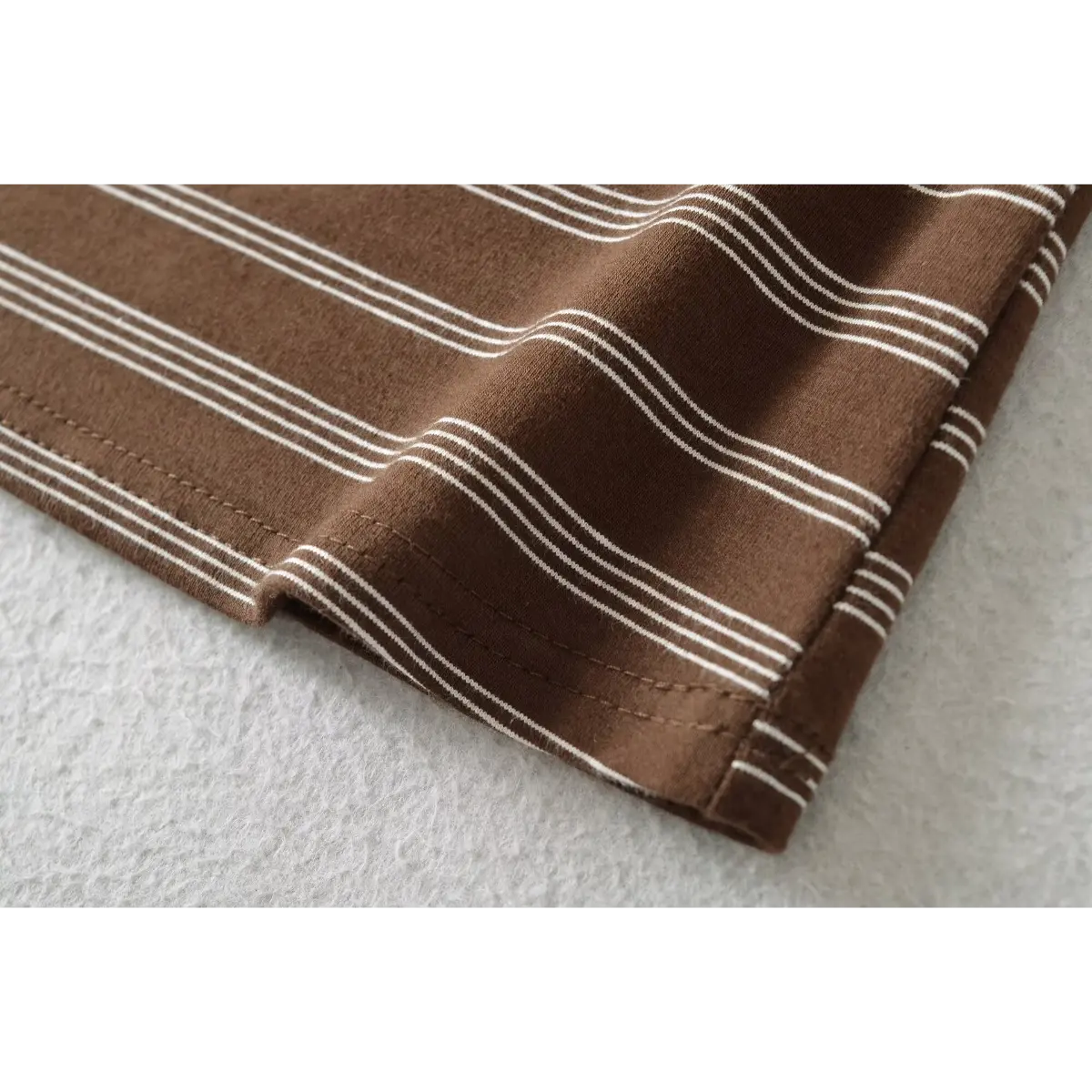 Close-up of the finished hem, showing the clean stitching and soft knit texture of the striped fabric.
