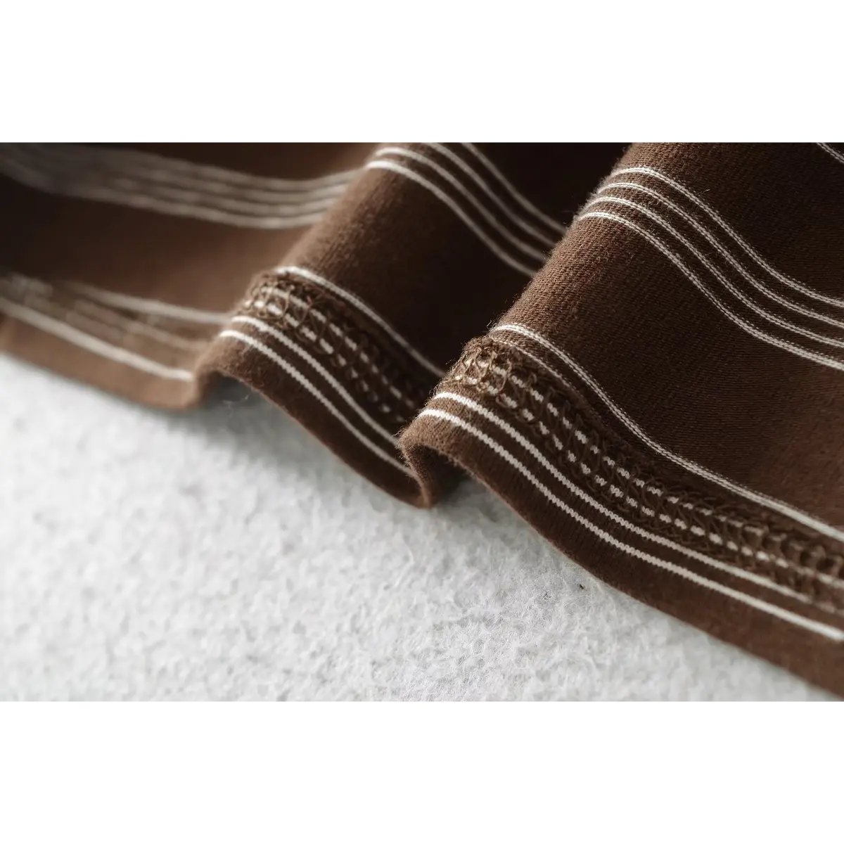Close-up of the hem stitching, showing the detailed finish on the brown striped fabric.