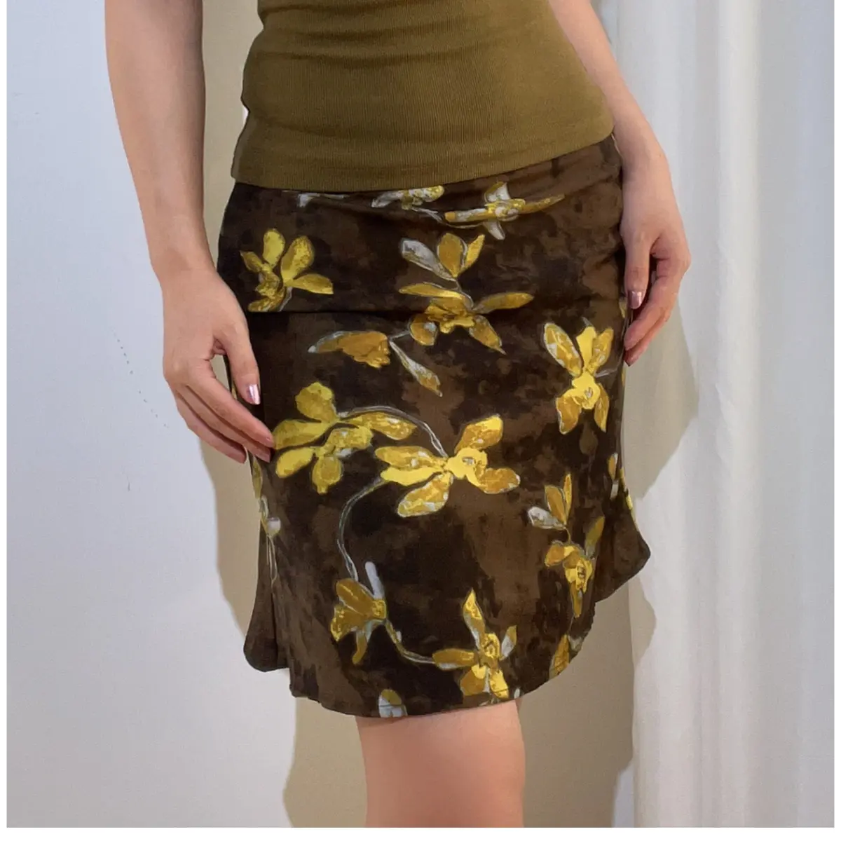 Close-up front view of a brown and yellow floral chiffon mini skirt, showing the print, fabric texture, and fit.