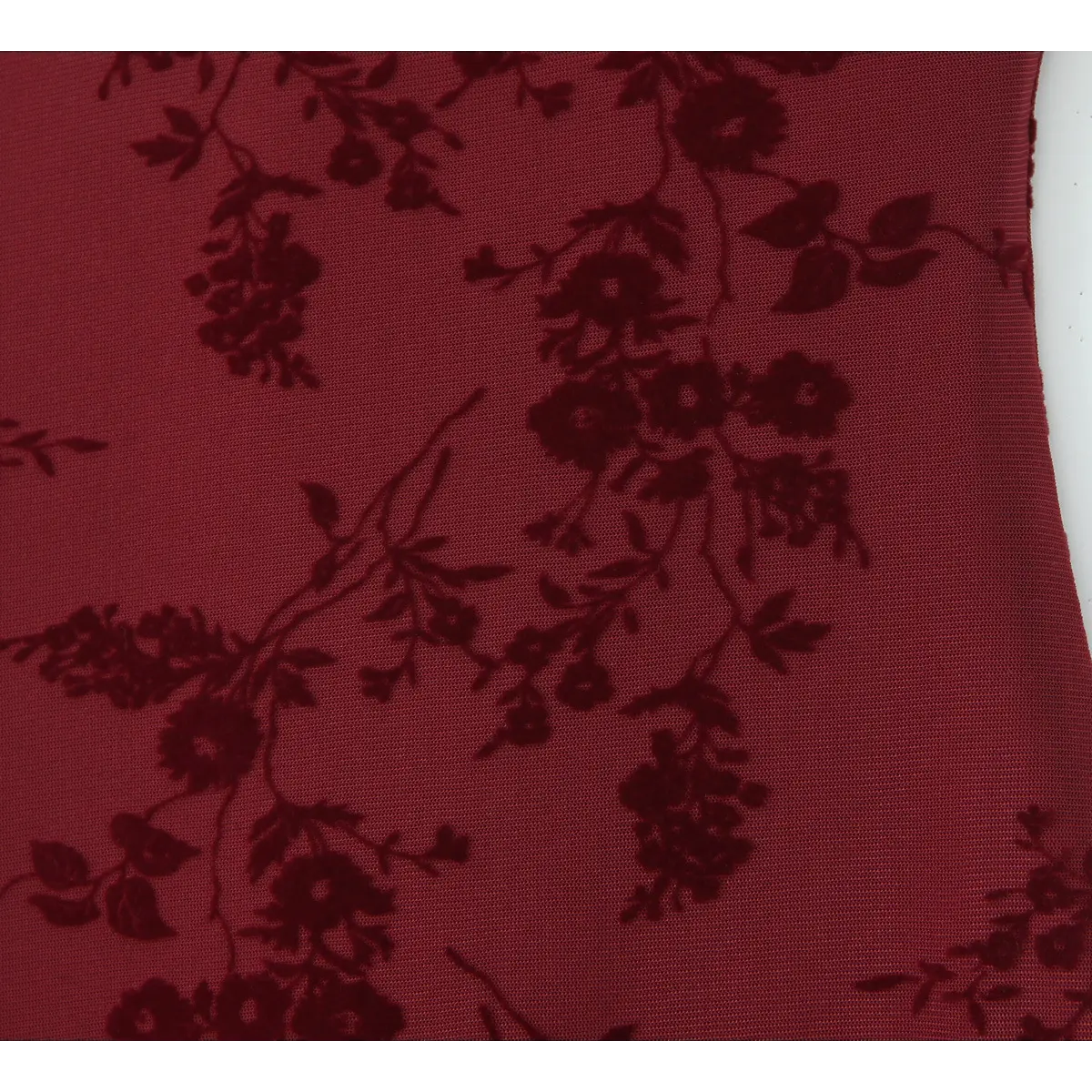 Close-up of the dark floral flocked print on the burgundy cami dress fabric.