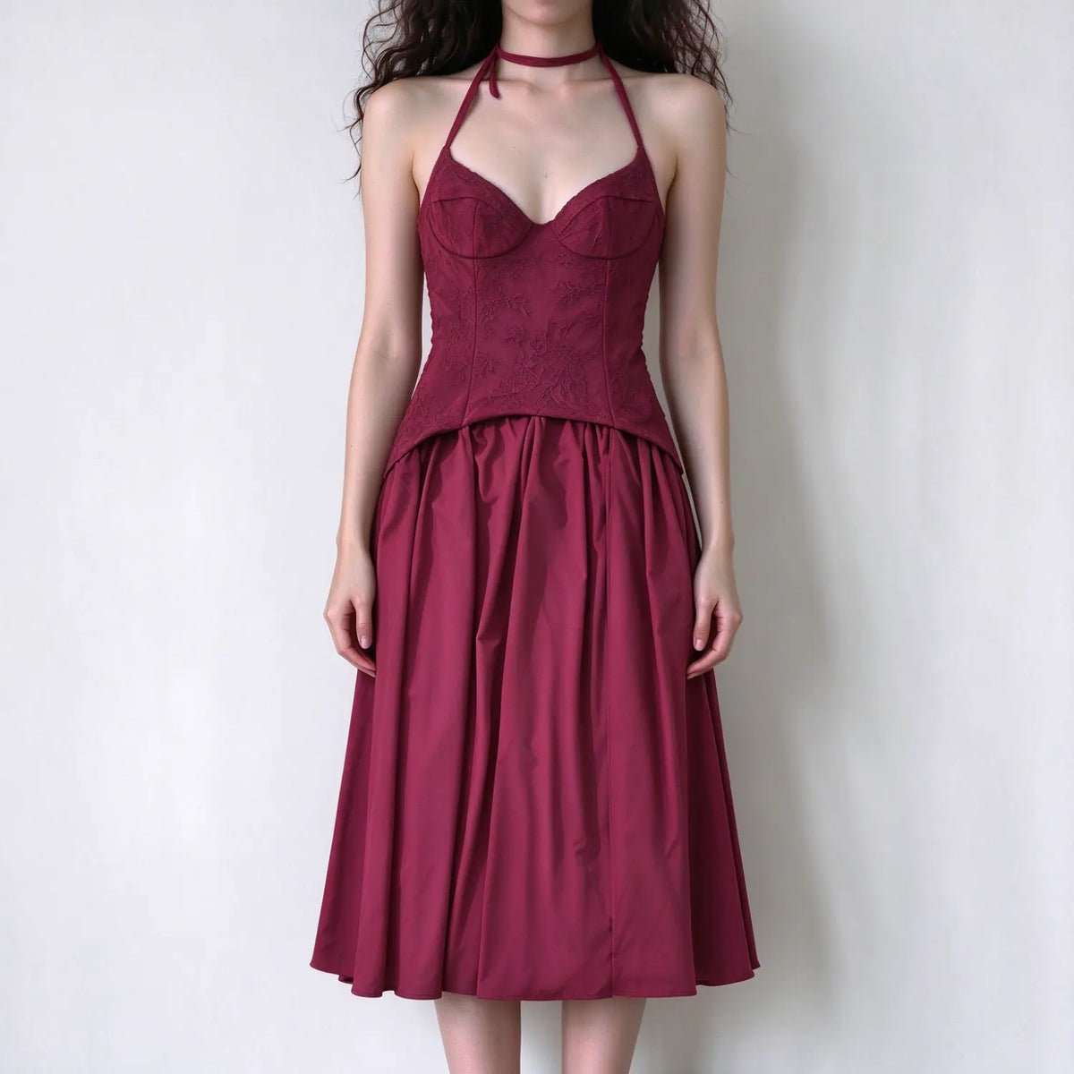 Model wearing burgundy halter corset maxi dress, lace embroidered bustier top, full flowy maxi skirt, halter choker tie detail, solid white background