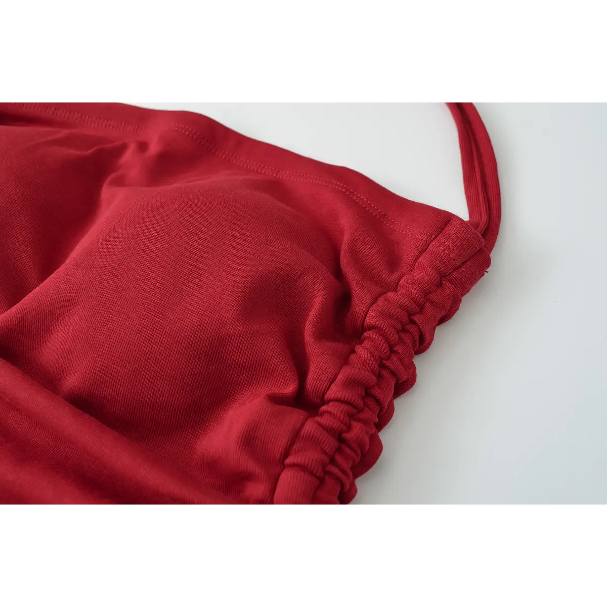 Close-up of the elasticated ruching on the side of the burgundy halter top.