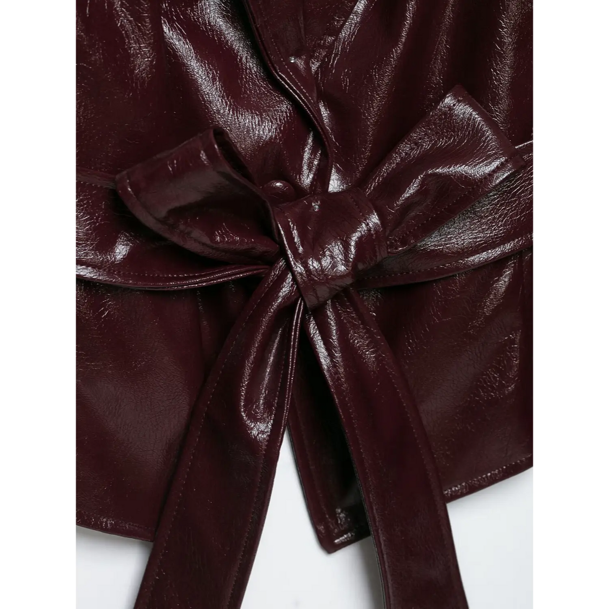 Close-up of self tie belt knotted at waist on burgundy leather blazer