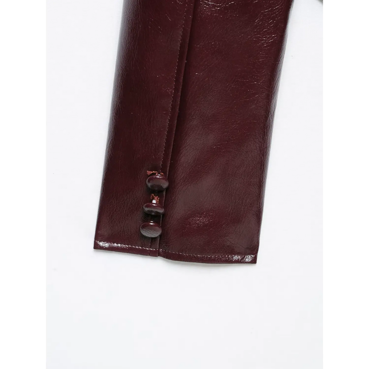 Close-up of three matching buttons at cuff on burgundy leather blazer