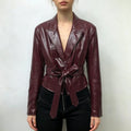 Model wearing burgundy leather look blazer with self tie belt and black trousers