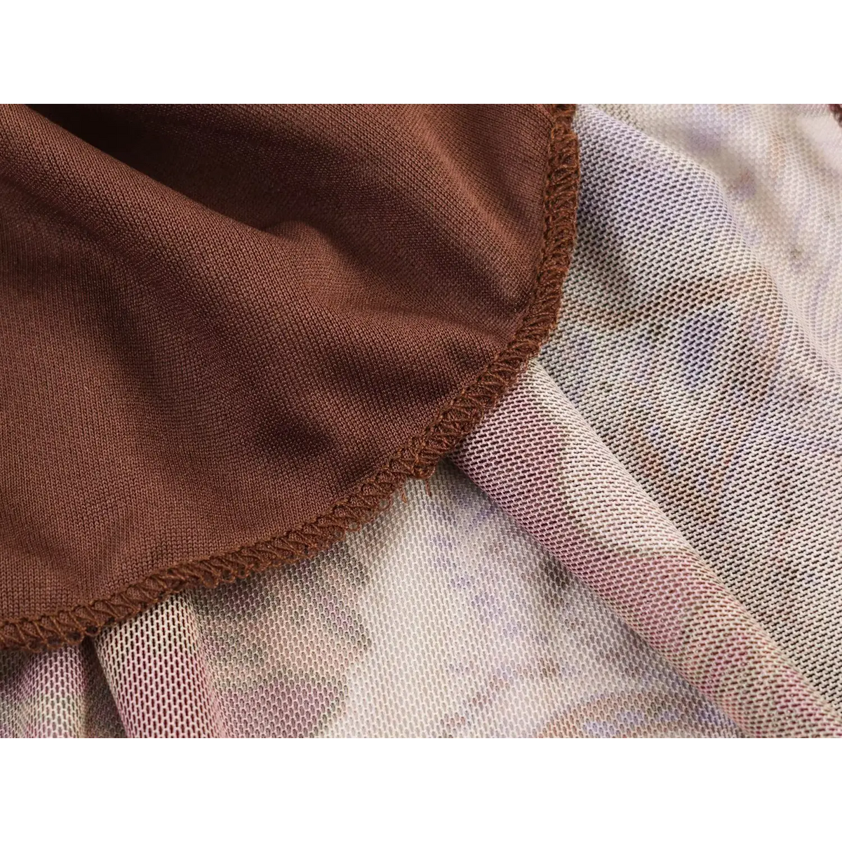 Macro shot of brown inner lining and mesh outer layer overlock stitching detail on paisley maxi dress