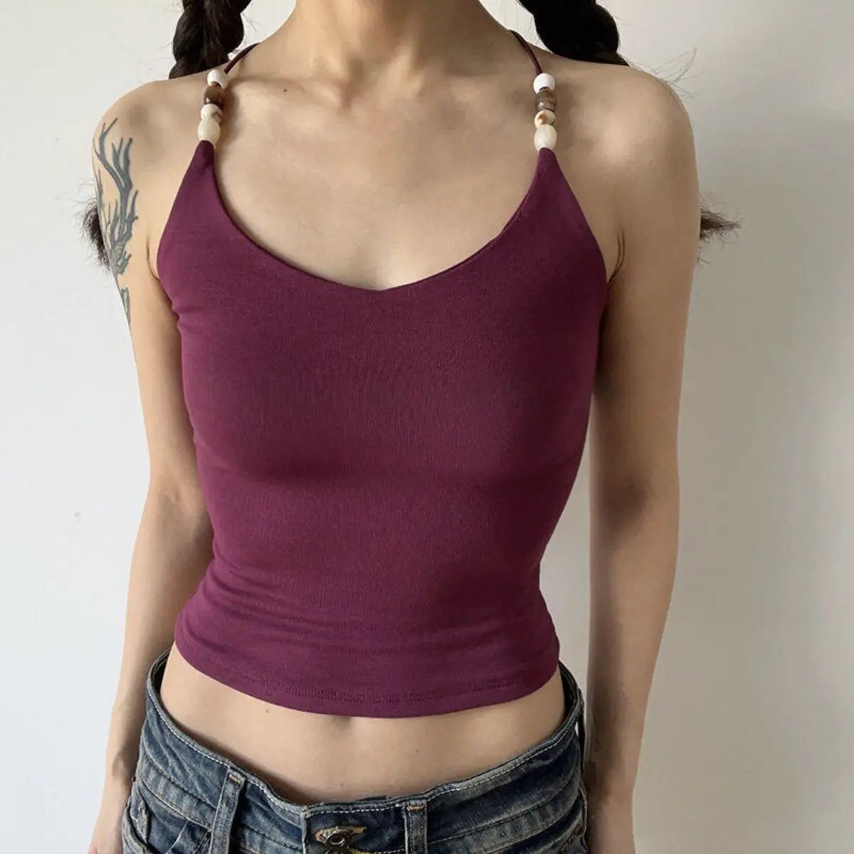 Lifestyle shot of burgundy ribbed camisole with beaded straps and crisscross back