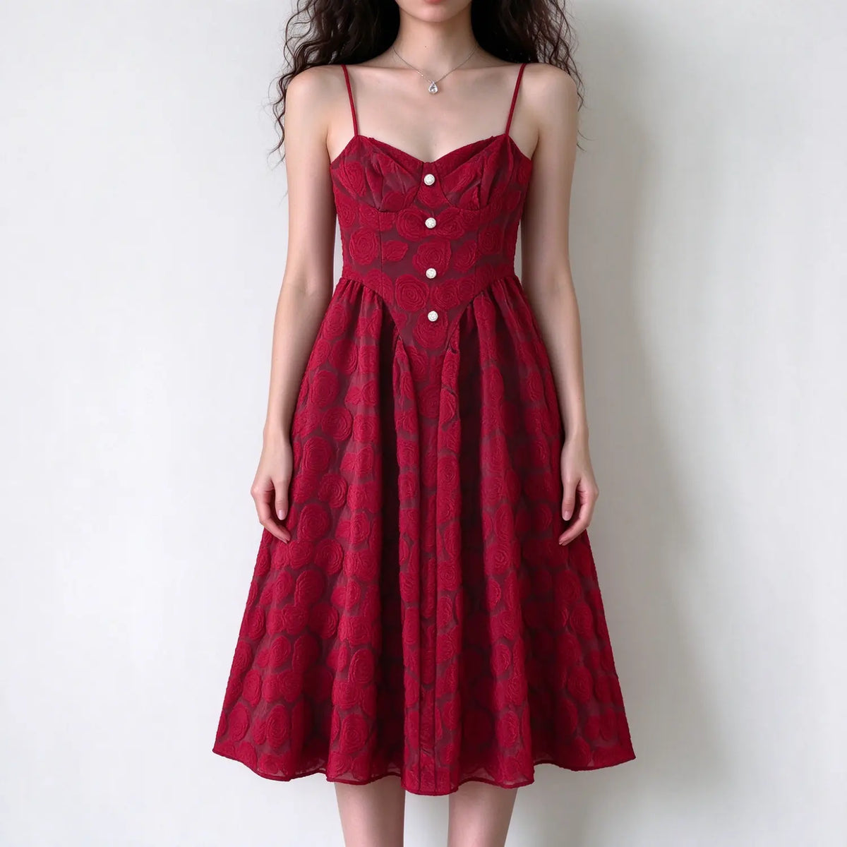 Model wearing burgundy spaghetti strap maxi dress, rose embossed texture, sweetheart neckline, front pearl buttons, flared maxi skirt