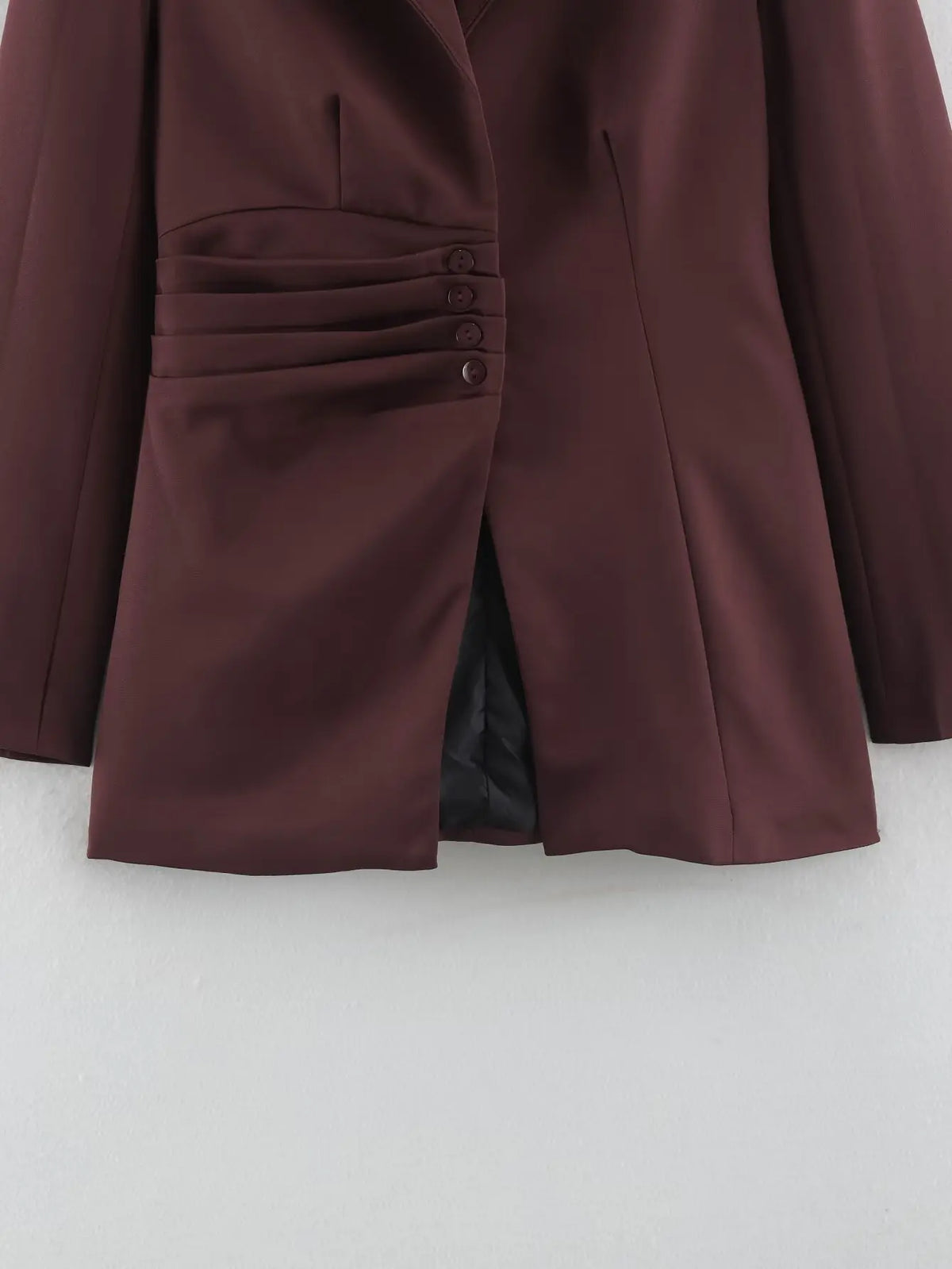 Close-up of asymmetrical ruched waist buttons and vent