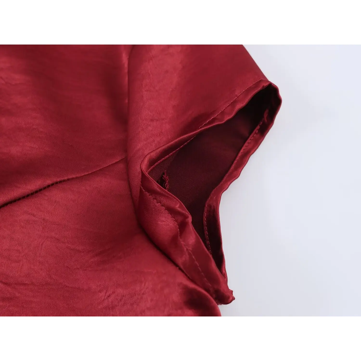 Sleeve cuff close-up, folded bound edge stitching, full matching burgundy inner lining, wrinkle textured glossy outer fabric