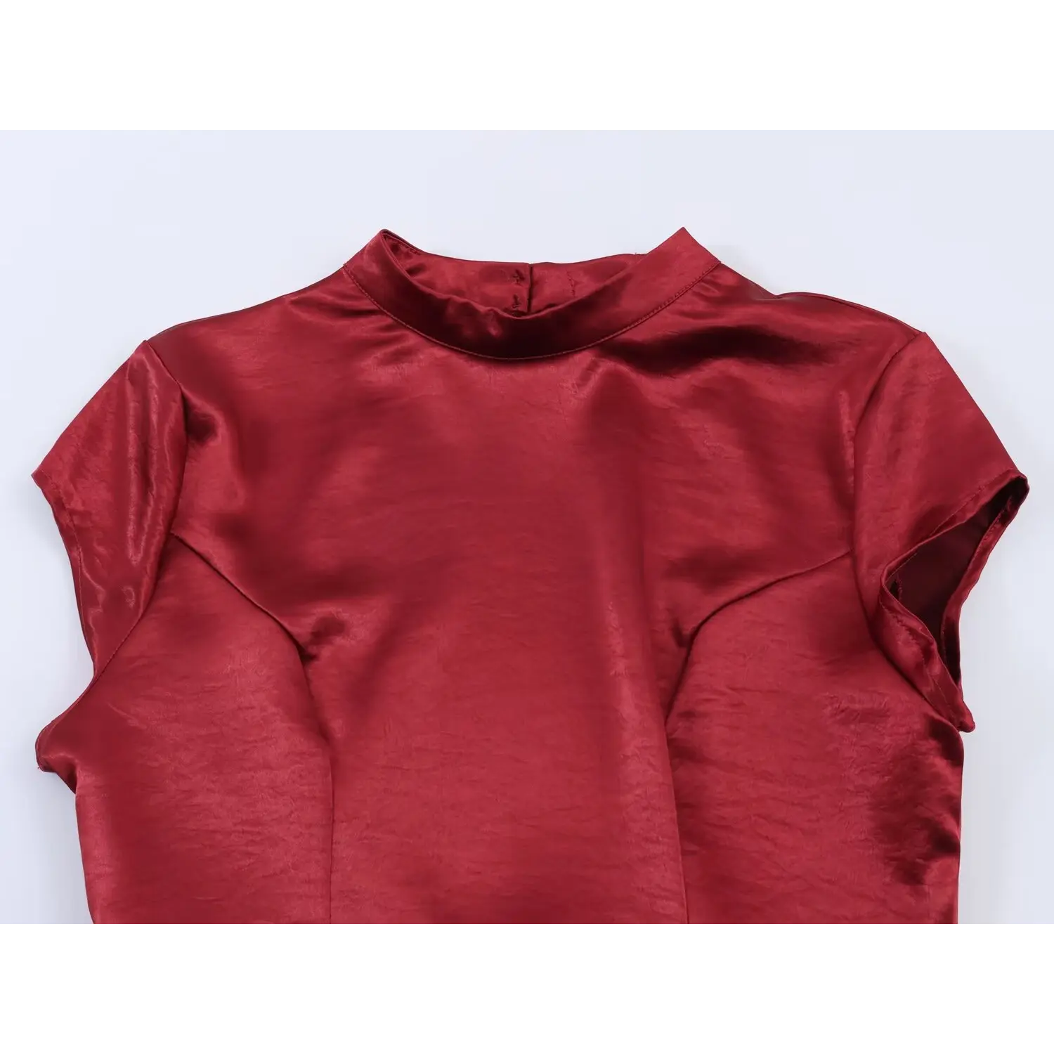 Upper front flat view, slim stand mock neck, tiny cap short sleeves, vertical bust tailored darts, subtle natural crinkle satin luster, back neck single button closure