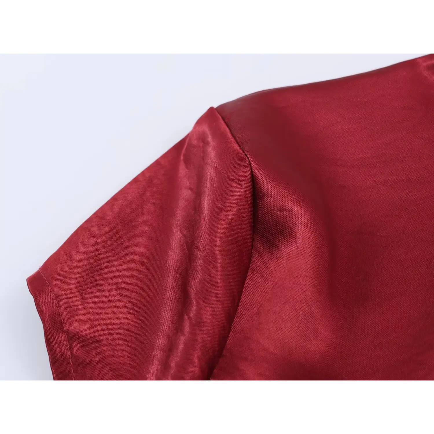 Shoulder cap sleeve junction macro, diagonal tailored bust seam, natural subtle crease satin with soft sheen, dense twill weave texture