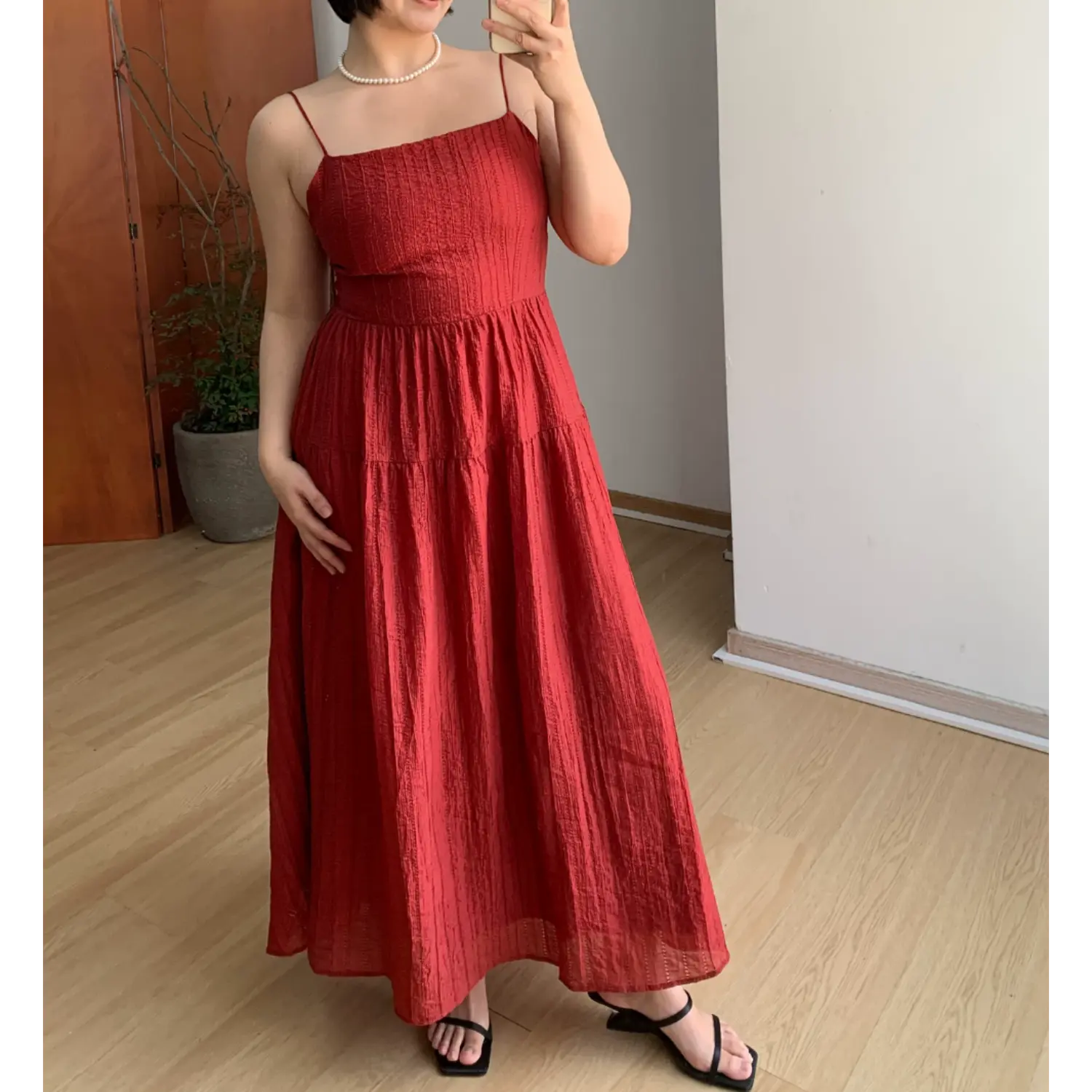 Straight front indoor mirror lifestyle photo of rich red vertical textured tier maxi slip dress, fitted empire waist, flowy layered floor skirt, paired with thin black heeled slide sandals