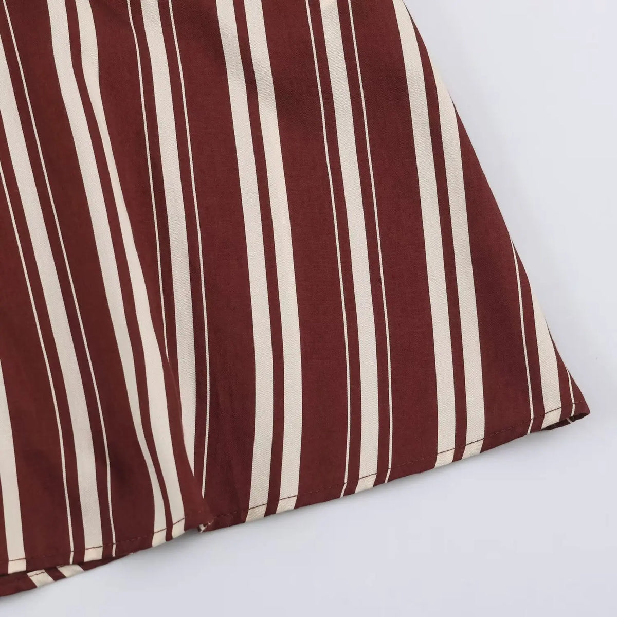 Close‑up of finished hem of burgundy and cream vertical stripe maxi dress skirt