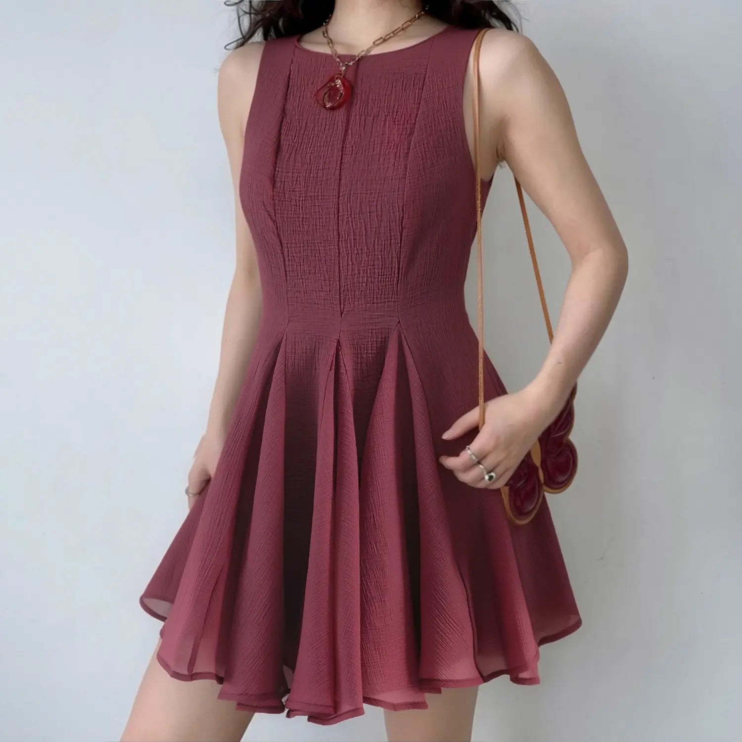 Model daily shot matte wine red textured sleeveless mini dress, simple round neck, vertical tailored waist darts, full bouncy A-line skirt, styled with vintage red pendant chain & butterfly shoulder bag, soft romantic date outfit