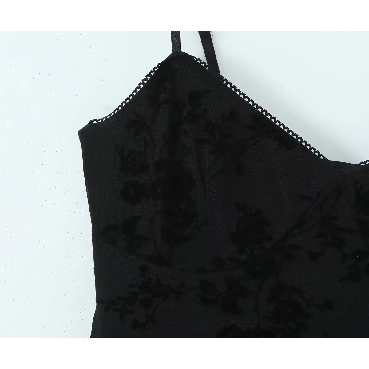 Close-up of the bust on a black flocked floral slip dress, highlighting the velvet floral pattern and mesh fabric texture.