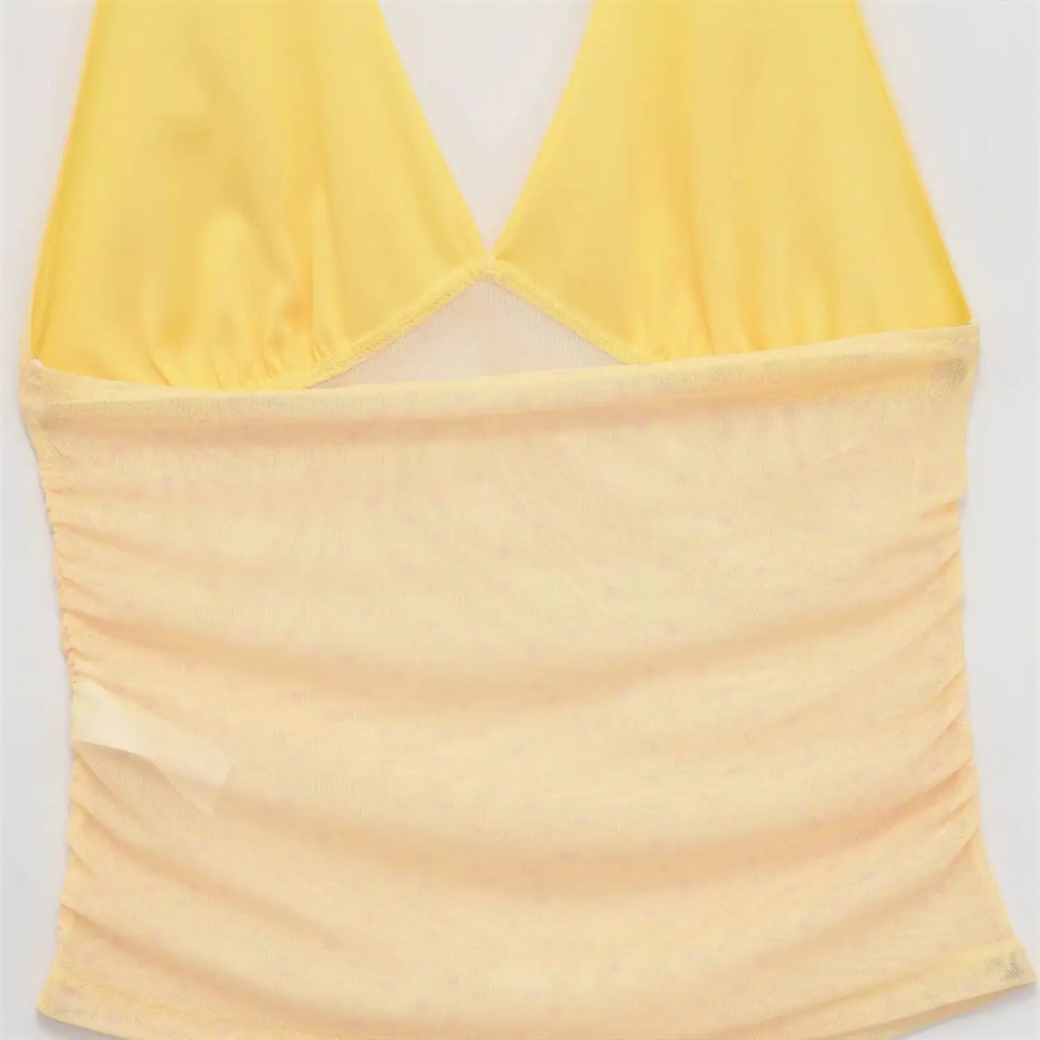 Bust gathering macro shot, pale yellow sheer mesh with tiny dots, soft ruched texture, fine stretch knit lining