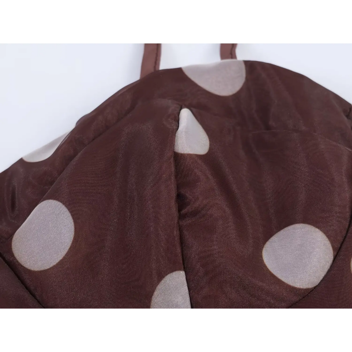 Close-up of bust seam and gathered structure on brown sheer polka dot maxi dress