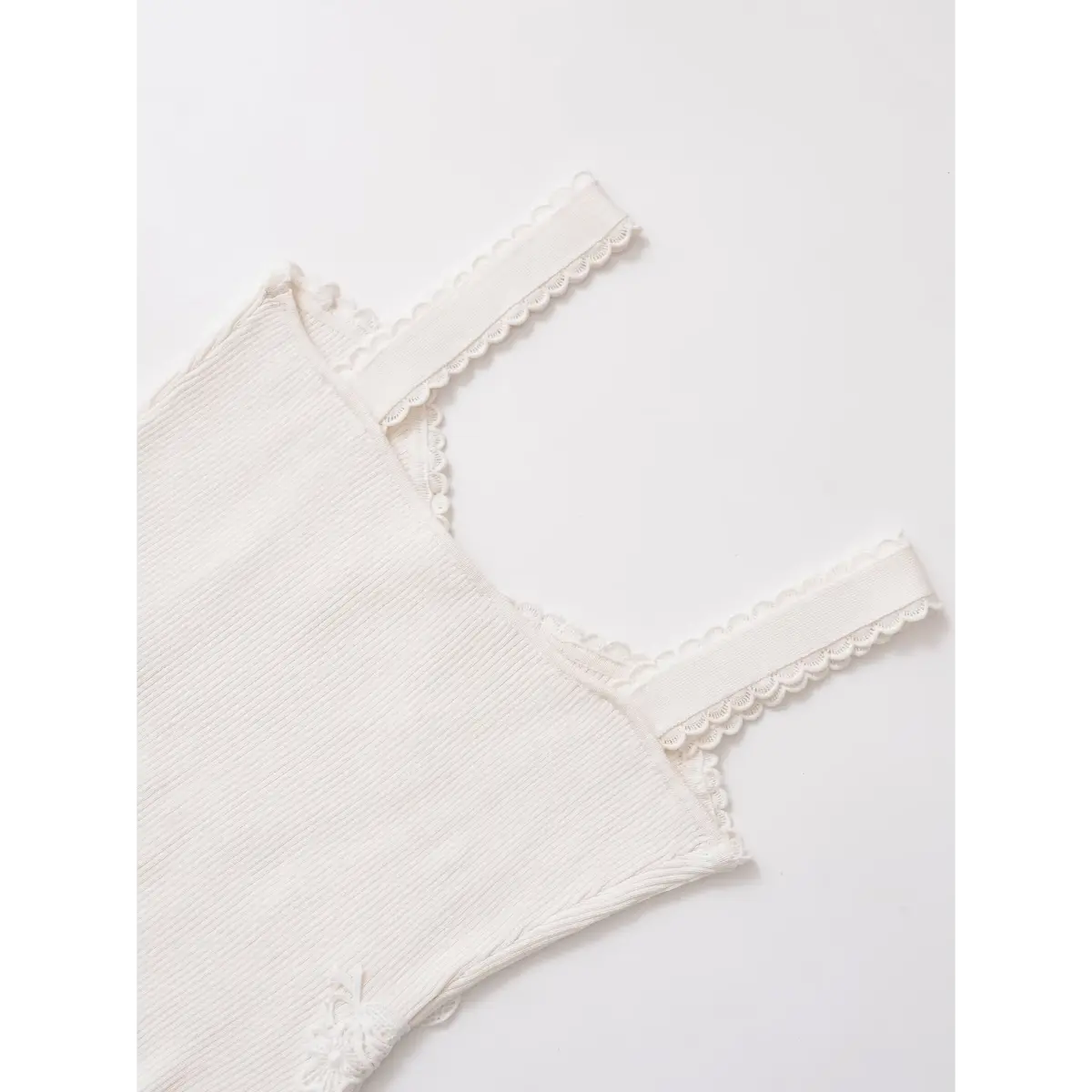 Top-down view of the bustier-style bodice and scalloped lace straps on a white ribbed cami top.