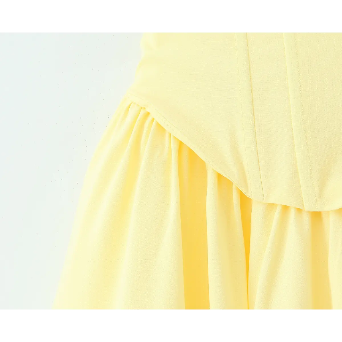 Close-up of the waist seam on a butter yellow strapless maxi dress, showing the structured bodice and gathered skirt transition.
