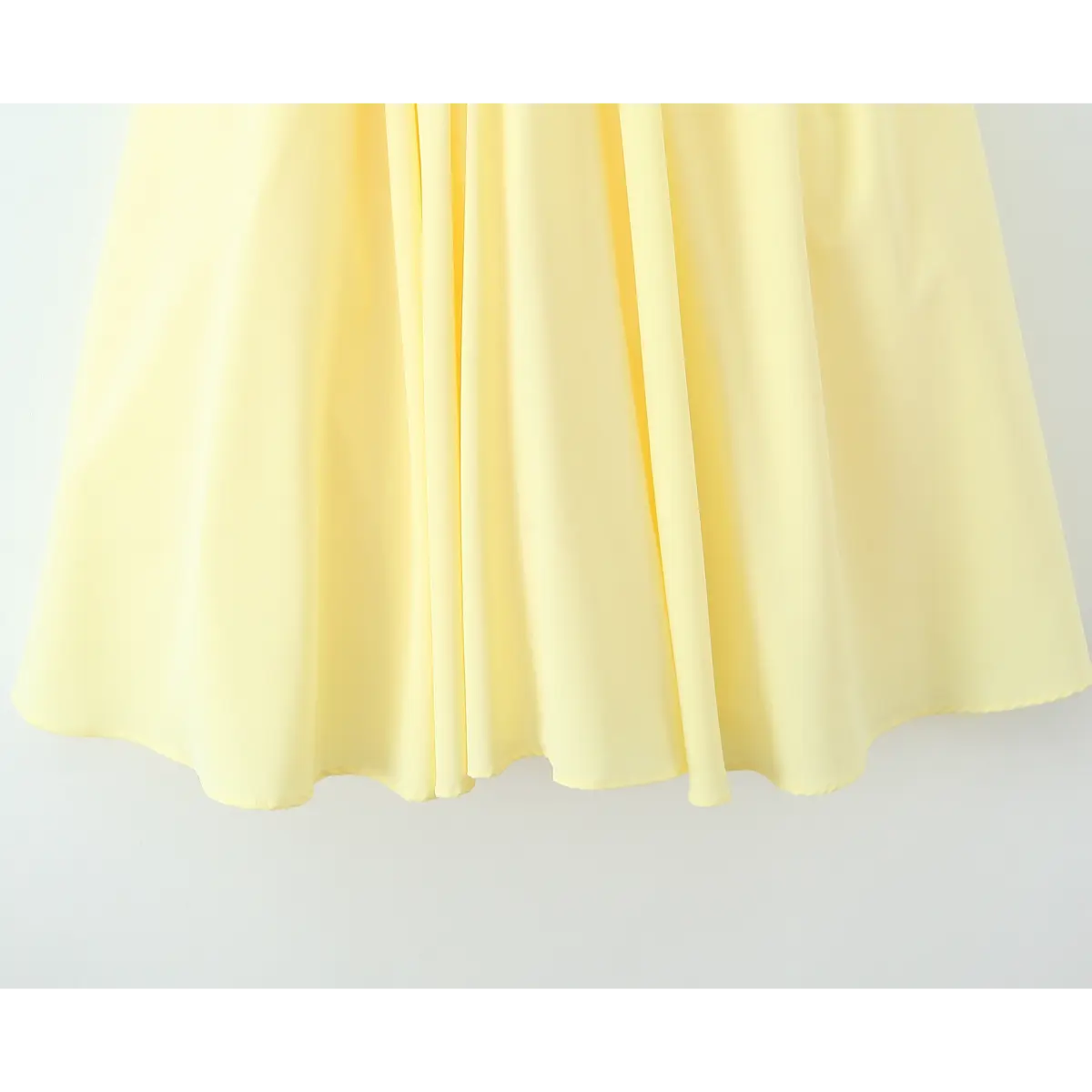 Close-up of the hem of a butter yellow strapless maxi dress, showing the clean finish and wide skirt silhouette.