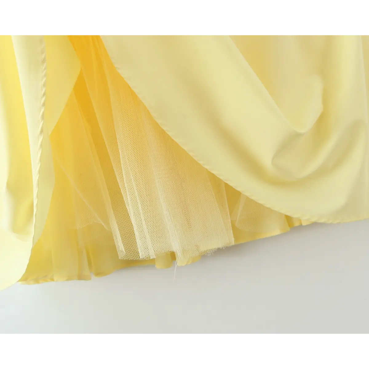 Close-up of the tulle lining visible under the skirt of a butter yellow strapless dress.