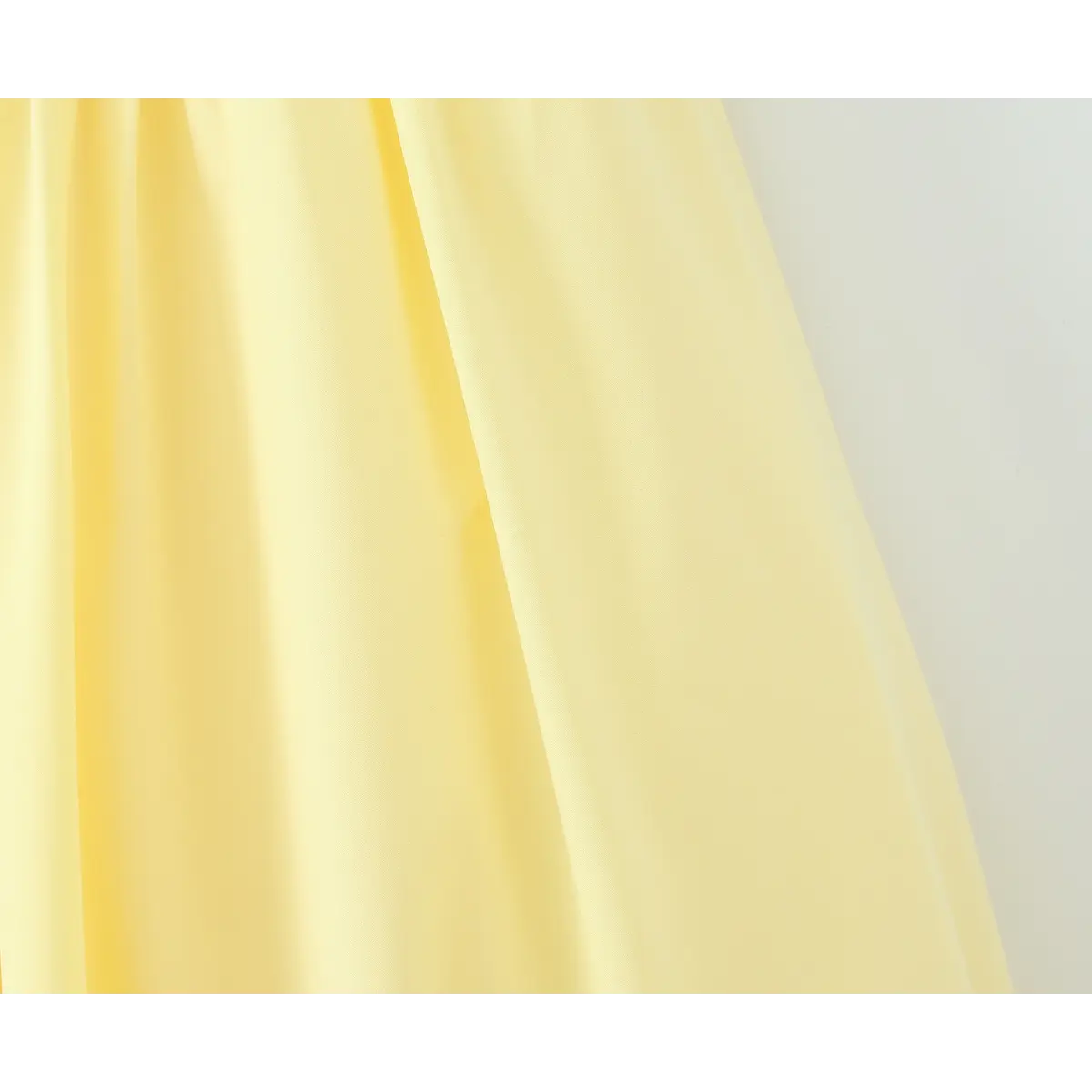 Close-up of the flowing skirt drape on a butter yellow strapless maxi dress, showing the soft fabric folds.