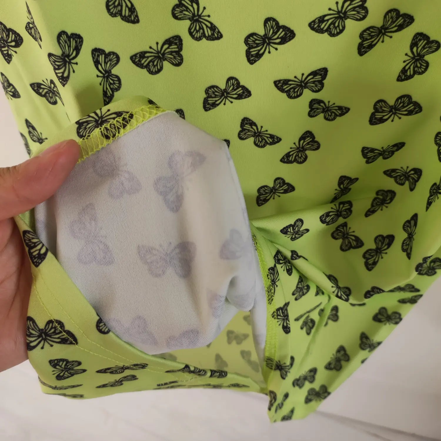 Close‑up inner lining fabric and construction detail lime green butterfly print bodycon dress
