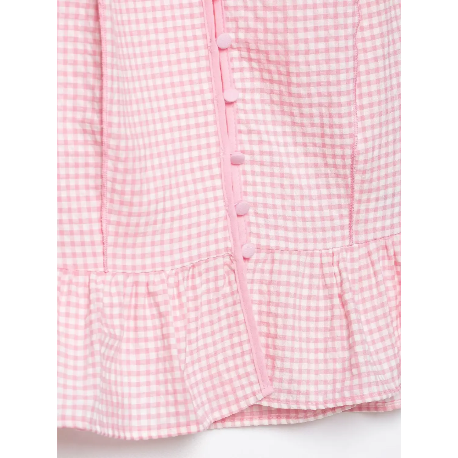 Lower torso partial view, front button row, transition seam to ruffled peplum hem, continuous gingham pattern