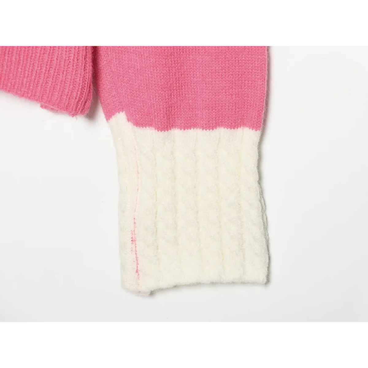 Macro detail of white cable knit cuff on pink colorblock knit cardigan