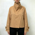 Female model wearing camel cropped jacket with draped asymmetrical stand collar and button cuffs