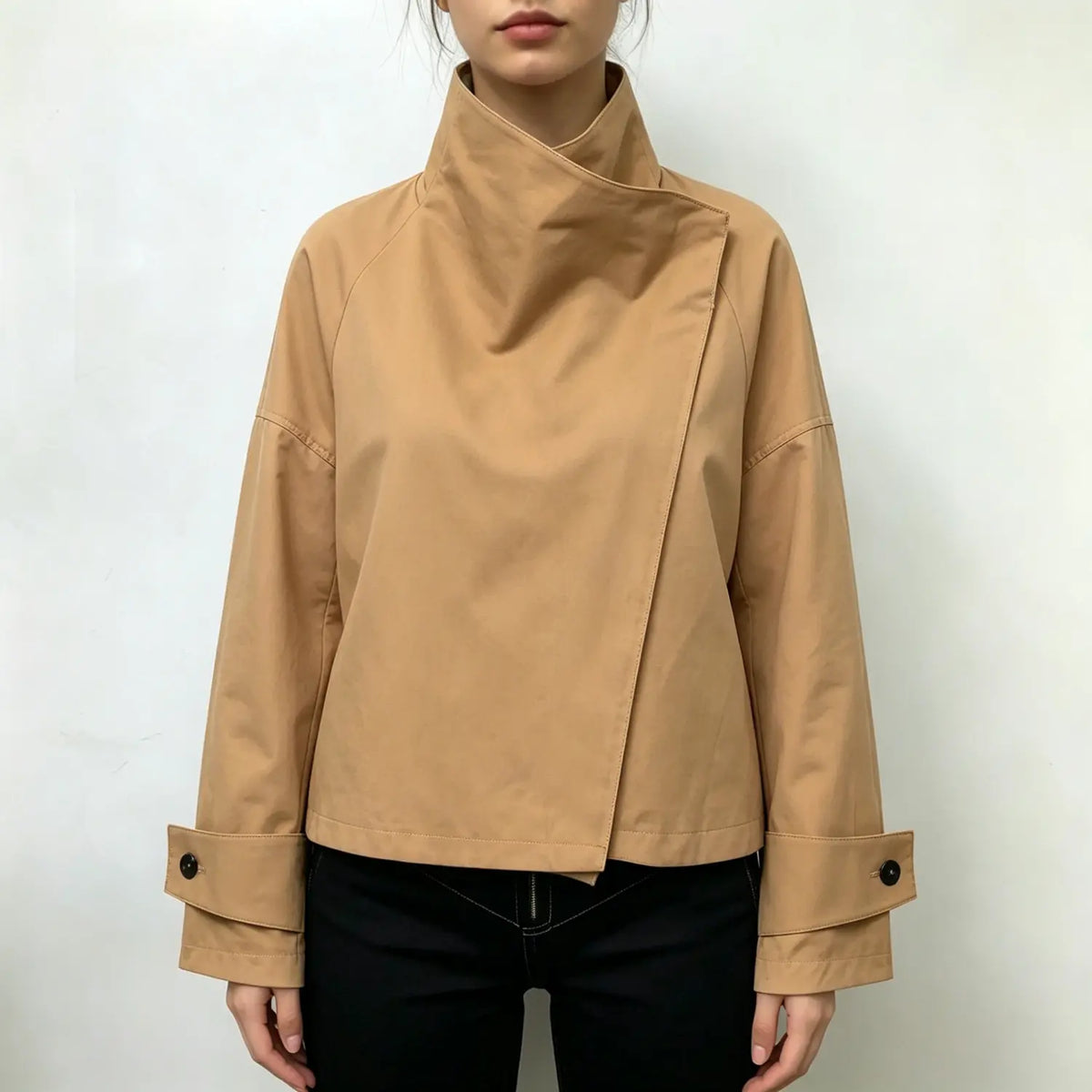 Female model wearing camel cropped jacket with draped asymmetrical stand collar and button cuffs