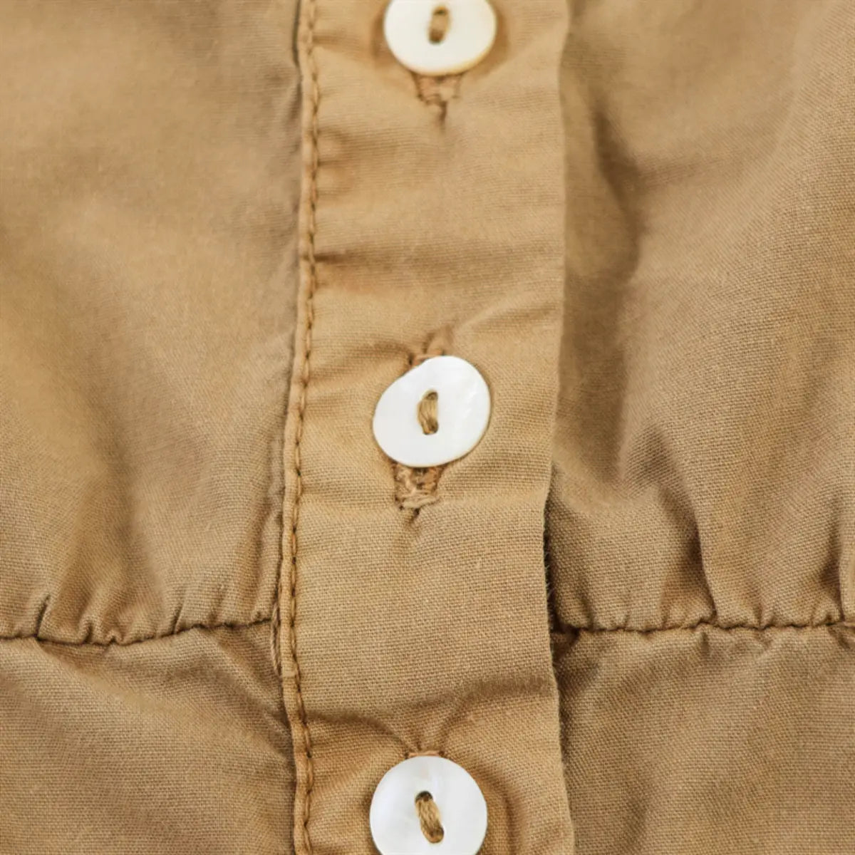 Close-up of the front button placket and fabric texture on the camel-colored top