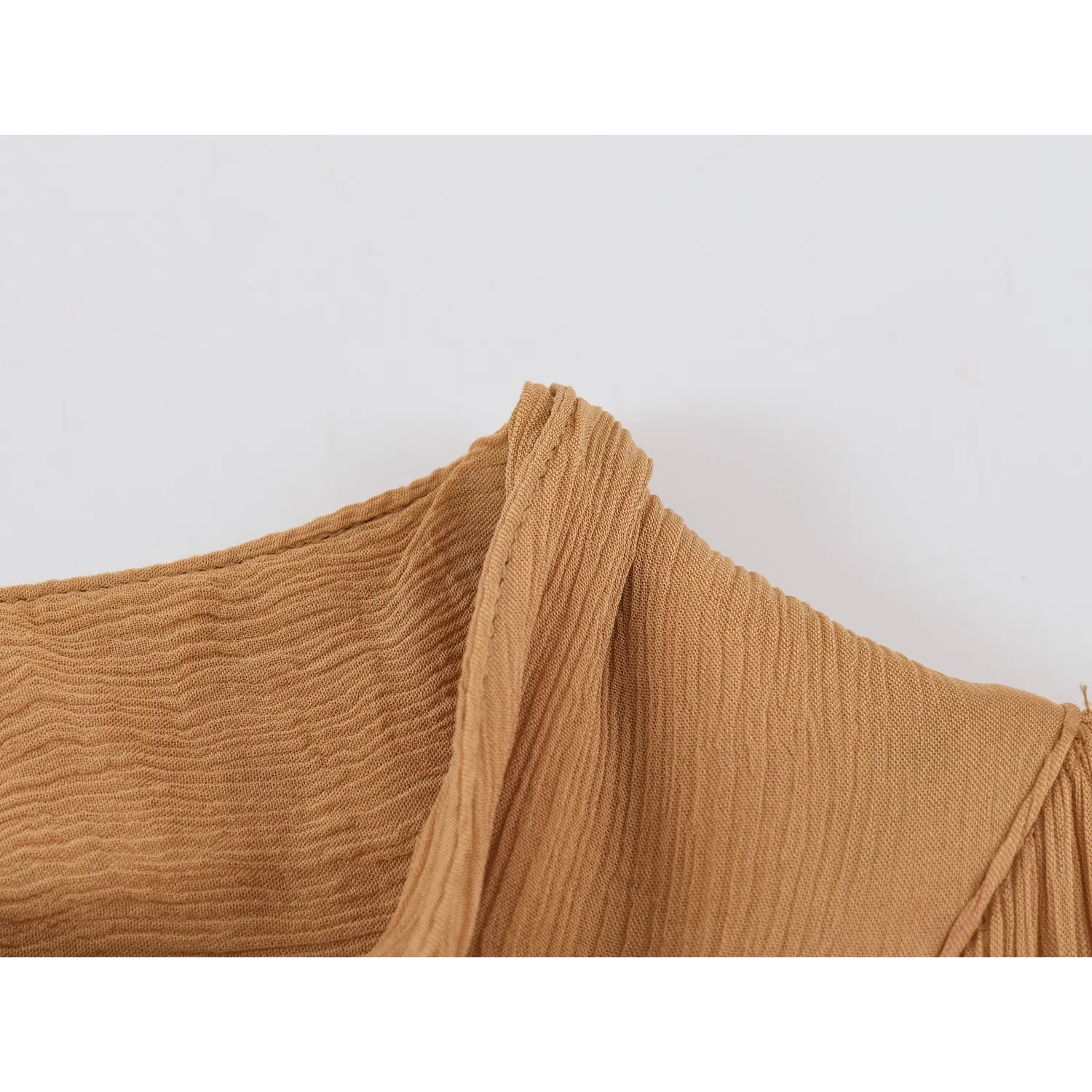 Close‑up of camel crinkled chiffon fabric texture and finished seam